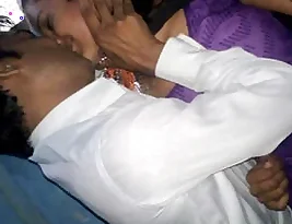 A romantic kiss of a farm based Indian couple in purple clothing.